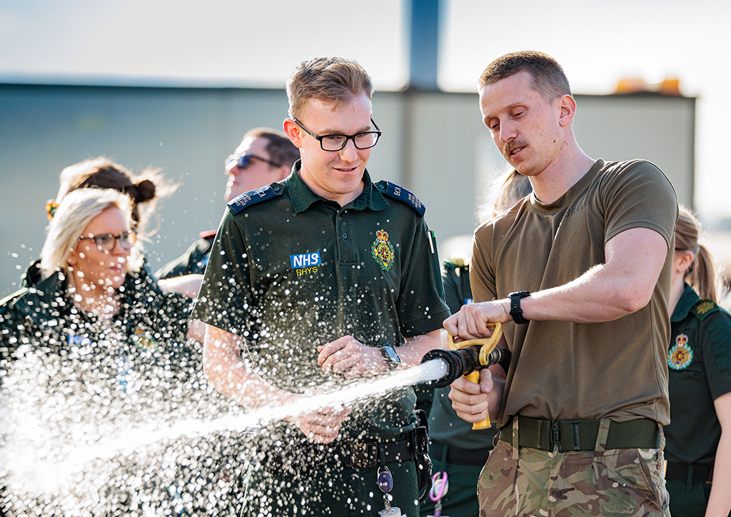 Members of the South Central Ambulance Service receive instruction on how to use a fire hose.